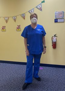Woman in blue medical scrubs in a school hallway