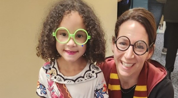 A little girl is dressed like Mirabel from the movie Encanto and a woman is dressed like Harry Potter.