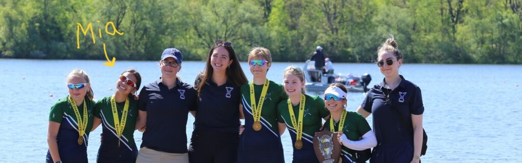 Nine people on stand on a dock after a rowing event