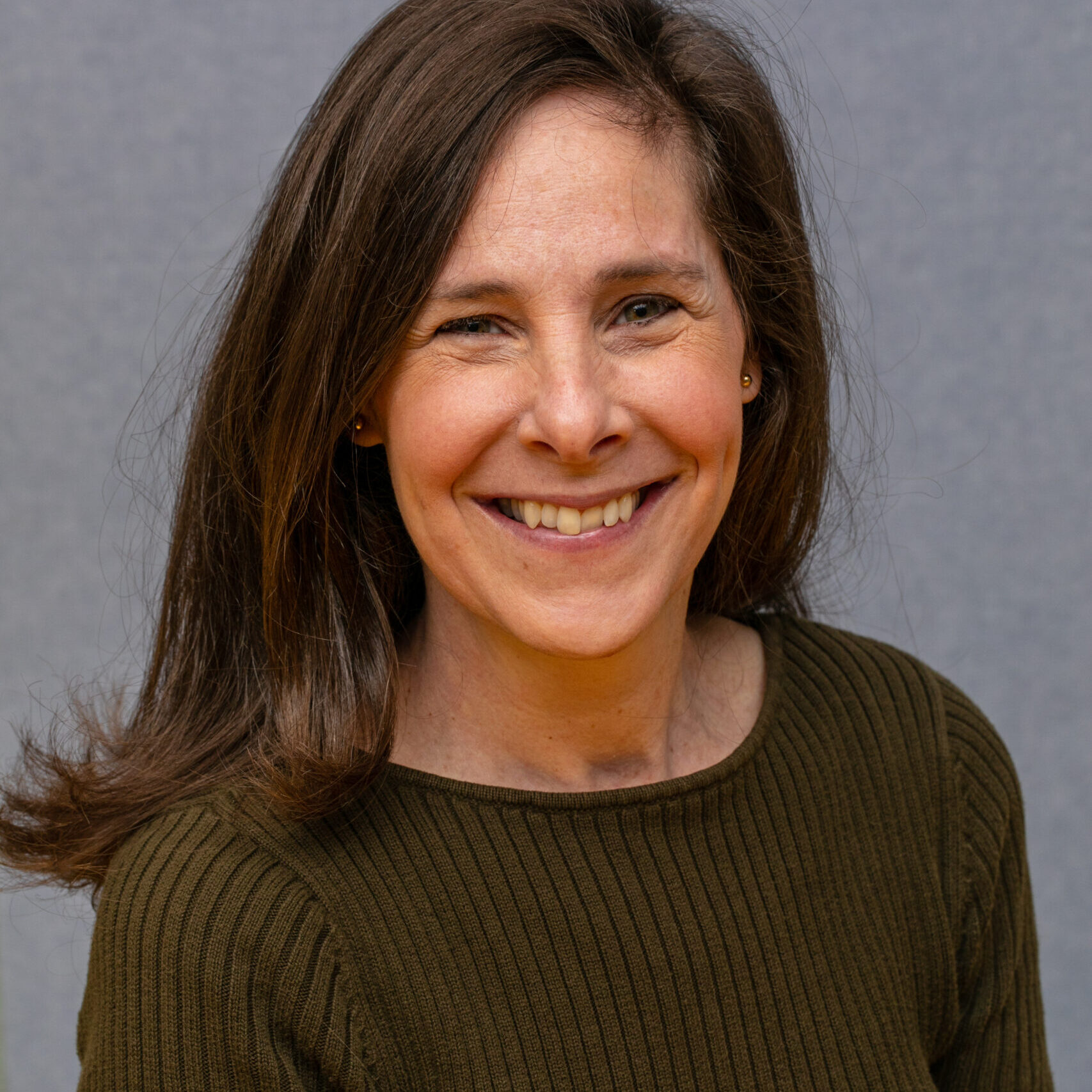 Dark-haired woman in brown shirt smiling