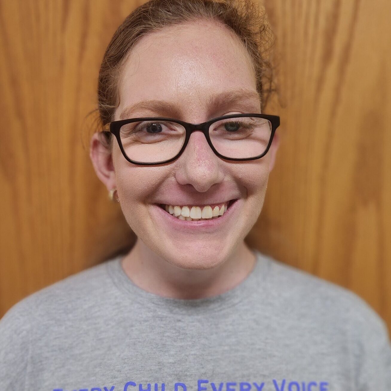 Smiling woman with glasses in a grey t-shirt
