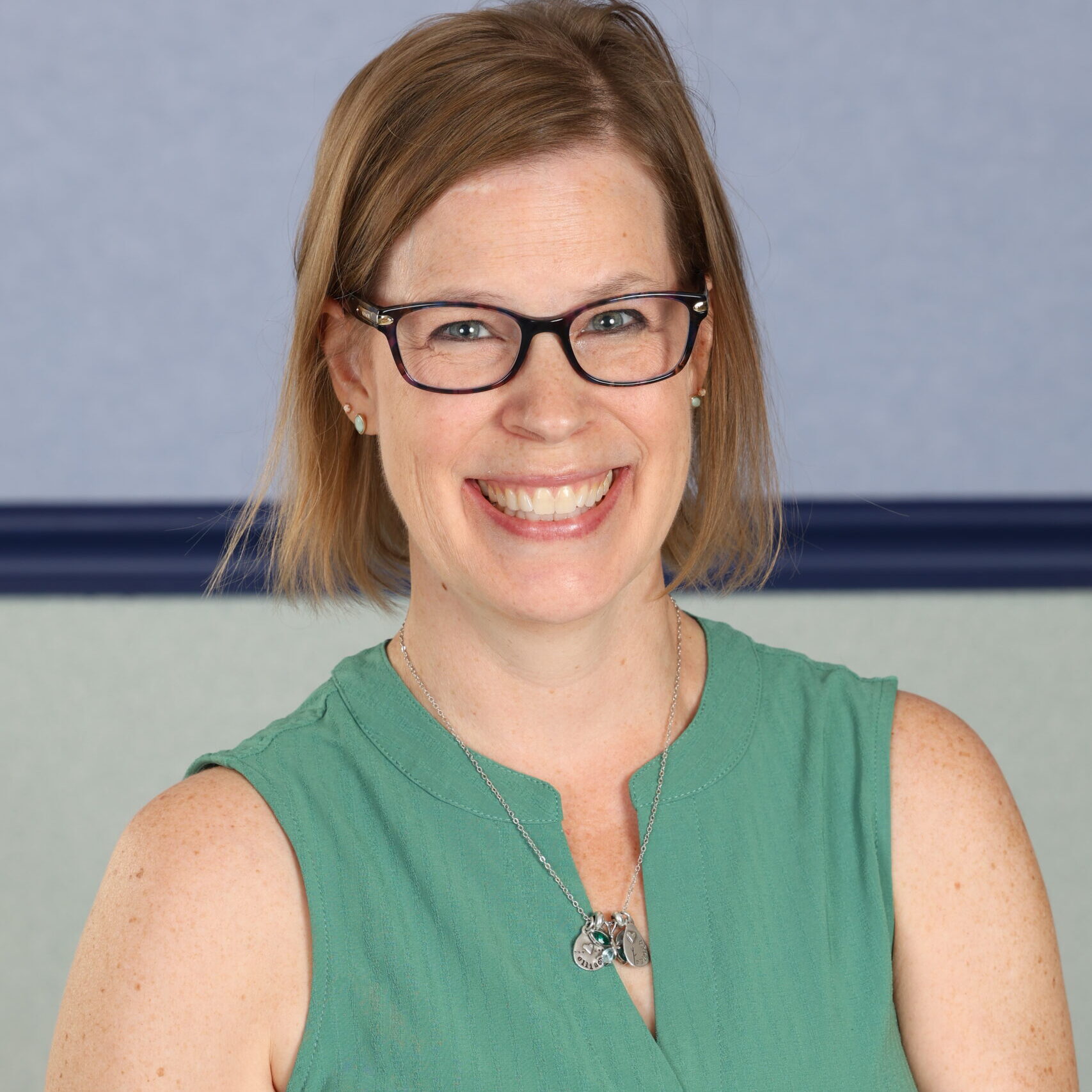 Headshot of a woman with glasses in a green shirt