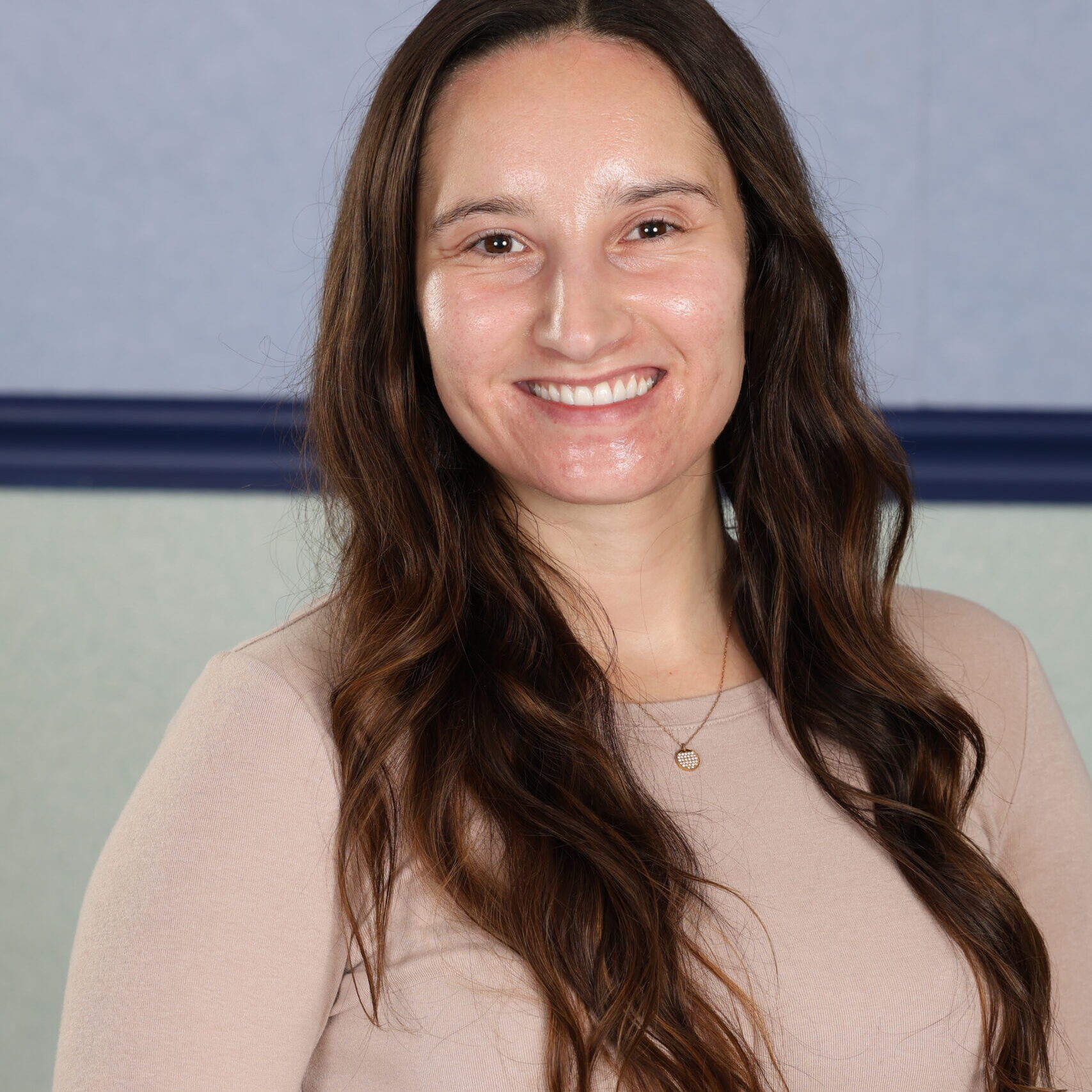 Headshot of woman with long brown hair in a beige shirt